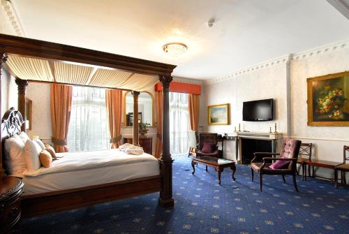 a bedroom with a bed and a desk and a television at Grand Royale Hyde Park in London