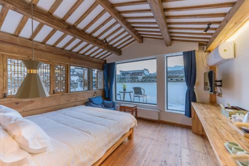 a bedroom with a bed and a large window at Huangshan Xidi Shang De Tang in Yi