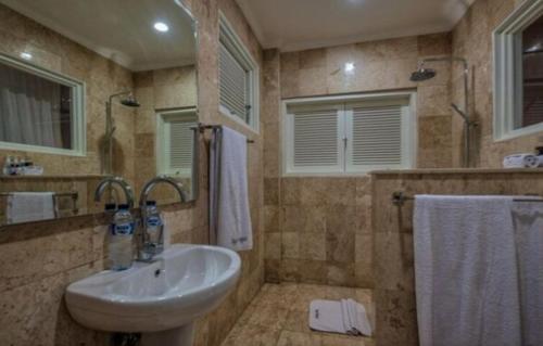 y baño con lavabo, espejo y toalla. en Bayu Cottages en Amed