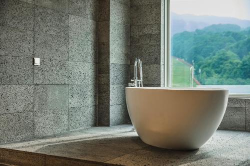 a bath tub sitting in front of a window at Phoenix Hotel Pyeongchang in Pyeongchang 