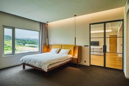 a bedroom with a large bed and a large window at Phoenix Hotel Pyeongchang in Pyeongchang 