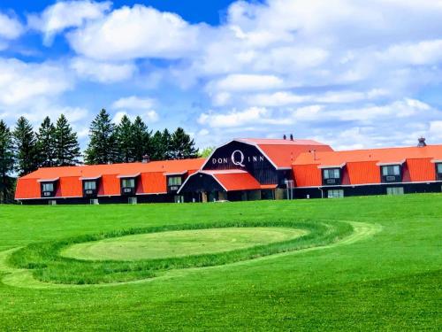 a building with red roofs on a green field at Don Q Inn in Dodgeville