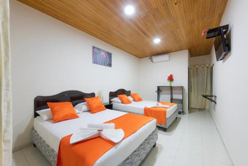 Hotel Colonial Villavieja في فيلافيجا: غرفة نوم بسريرين مع وسائد برتقالية