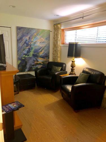 a living room with two chairs and a television at Gibsons Harbour Retreat in Gibsons