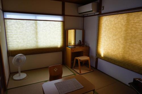Habitación con 2 ventanas, silla y escritorio. en Lumiere De Bonnart en Okayama