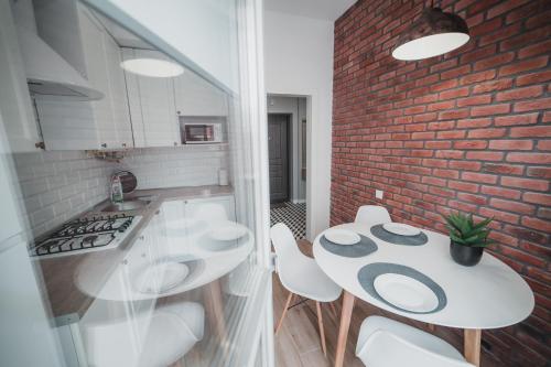 kuchnia z białym stołem i krzesłami oraz ceglaną ścianą w obiekcie Apart-hotel Kostjukowski Apartments Nizhynska 17 w Lwowie