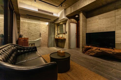 a living room with a leather couch and a flat screen tv at Echovilla B&B II in Hualien City