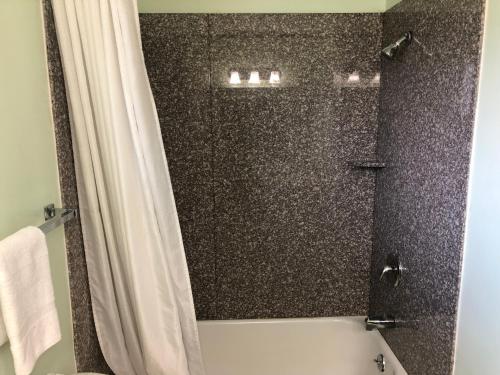 a bathroom with a shower with a white shower curtain at Klamath Motor Lodge in Yreka