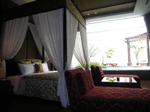 um quarto com uma cama de dossel com uma cadeira e uma janela em Mos Motel em Zhongli