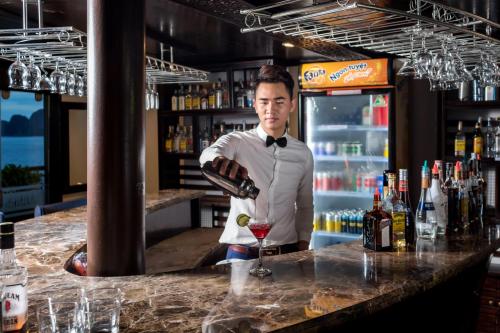 a man standing behind a bar with a glass of wine at Alisa Premier Cruise in Ha Long