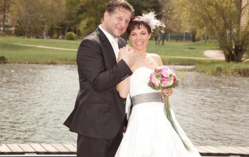 a bride and groom posing for a picture in front of a pond at Pension Schierl in Faistenau