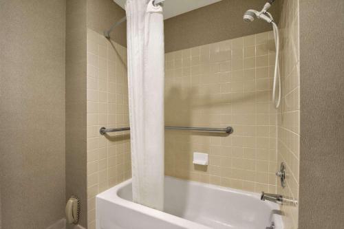 a bathroom with a white tub and a shower at Days Inn by Wyndham Auburn in Auburn