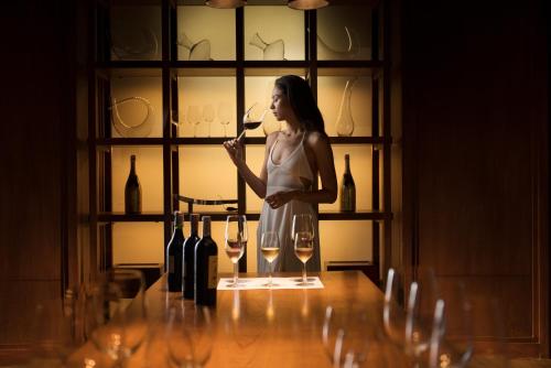 a woman standing in front of a counter filled with wine glasses at Anantara Layan Phuket Resort - SHA Extra Plus in Layan Beach