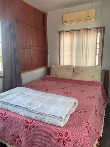 un letto in una stanza con una coperta rosa sopra di Mountain View Guesthouse a Sukhothai
