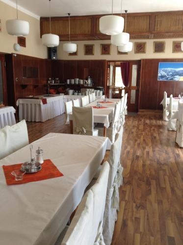 a dining room with white tables and white chairs at Hotel Krakonos in Rokytnice nad Jizerou