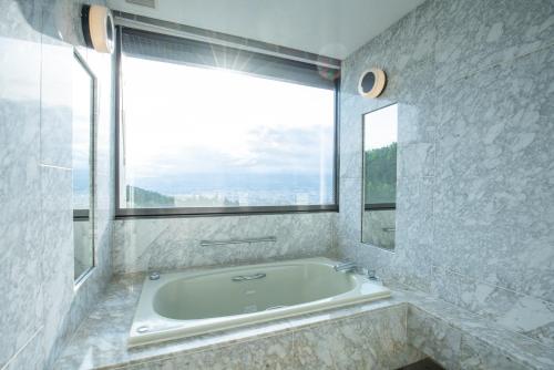 a bath tub in a bathroom with a large window at Rembrandt Premium Fuji Gotenba in Gotemba