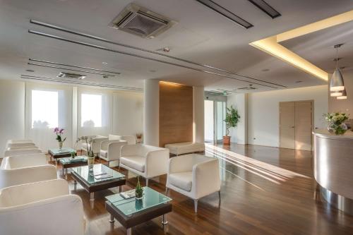 a waiting room with white chairs and tables and windows at Best Western Hotel San Marco in Siena