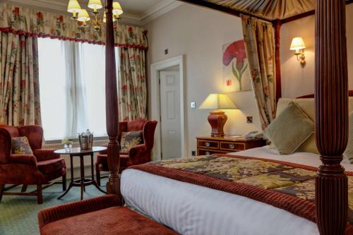 um quarto com uma cama de dossel, uma mesa e cadeiras em The Midland Hotel em Bradford