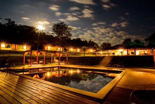 a swimming pool at night with lights in a park at Pousada Boyrá in Bonito