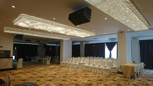 Habitación grande con sillas blancas y un escenario en InnB Park Hotel, en Kuala Lumpur