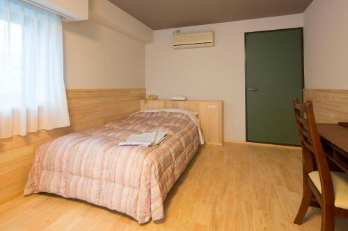 a bedroom with a bed and a desk and a table at Nanshukan in Kagoshima