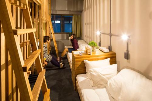 two people are sitting in a room with stairs at Nanshukan in Kagoshima