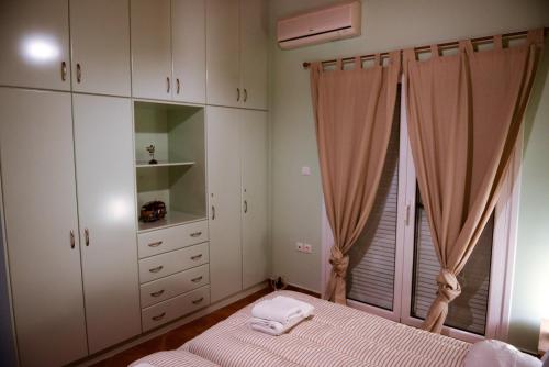 a bedroom with white cabinets and a bed and a window at Patras Cozy Lodge in Patra
