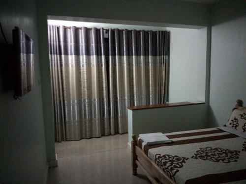 a bedroom with a bed and a window with curtains at Harod Suites in Kampala