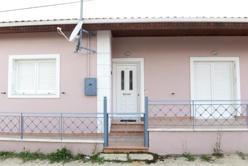 a white house with a gate and a door at Patras Cozy Lodge in Patra