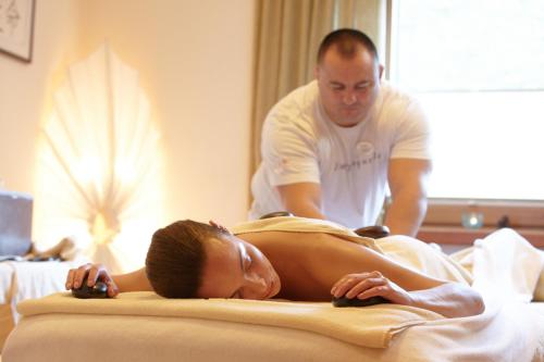 a man standing next to a woman laying on a bed at Hotel Alpin Spa Tuxerhof in Tux