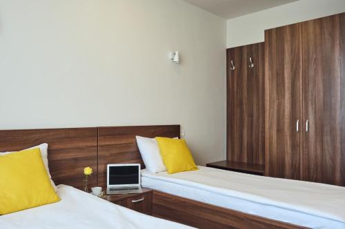 a bedroom with two beds with yellow pillows and a laptop at Boca Boutique Hotel in Timişoara