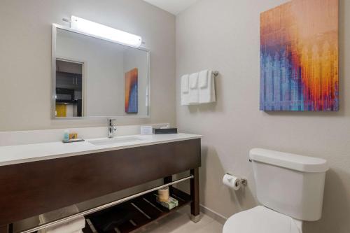 a bathroom with a sink and a toilet and a mirror at MainStay Suites Bricktown - near Medical Center in Oklahoma City