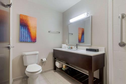 a bathroom with a sink and a toilet and a mirror at MainStay Suites Bricktown - near Medical Center in Oklahoma City
