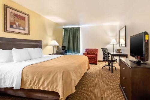 Habitación de hotel con cama, escritorio y TV. en Quality Inn & Suites Limon, en Limon