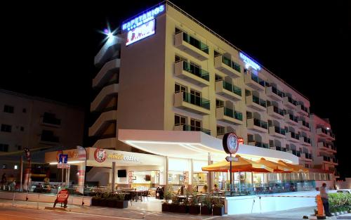 a hotel building with tables and umbrellas at night at Kapetanios Bay Hotel Protaras in Protaras