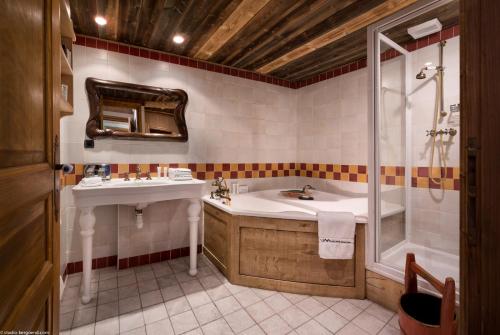 ein Bad mit einer Badewanne, einem Waschbecken und einer Dusche in der Unterkunft Hôtel Les Suites du Montana by Les Etincelles in Tignes