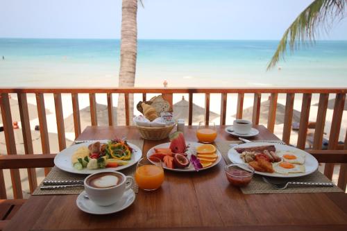 a table with plates of breakfast food on the beach at Banana Fan Sea Resort in Chaweng
