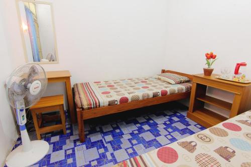 a bedroom with a bed and a desk and a fan at Griya Godean Syariah Yogyakarta in Bantul