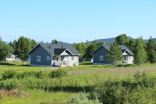 two blue and white houses in a field at Youth Center Vasatokka in Inari