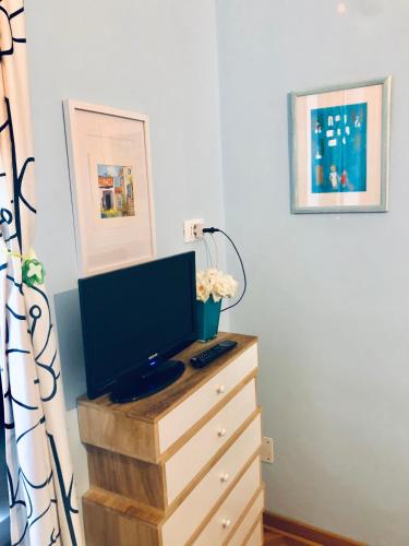 a television on a wooden dresser with a desk at Alla Scalinata del Teatro Rossetti parcheggio in Trieste