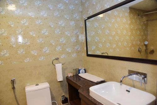a bathroom with a sink and a mirror and a toilet at The International Centre Goa in Panaji
