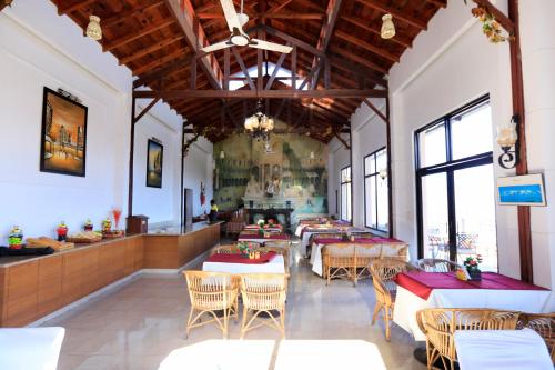 un comedor con mesas, sillas y ventanas en Woodsvilla Resort, en Rānīkhet