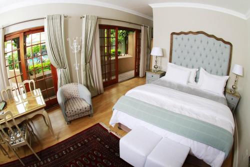 a bedroom with a large bed and a chair at Oleander Guest House in Kimberley