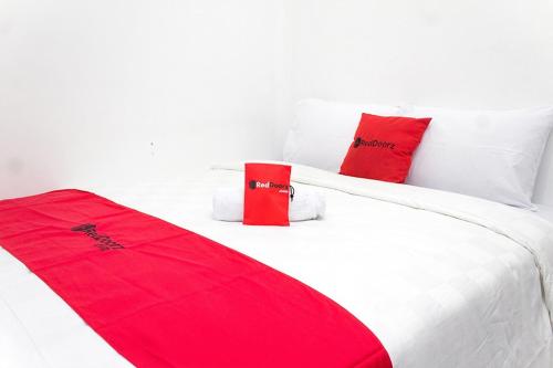a bedroom with two red pillows on a white bed at RedDoorz @ Galuh Mas in Karawang