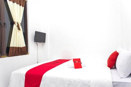 Cette chambre blanche comprend un lit avec une couverture rouge. dans l'établissement RedDoorz @ Galuh Mas, à Karawang