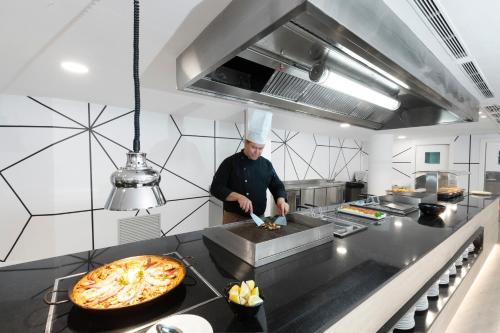 a chef preparing a pizza in a kitchen at Palmanova Suites by TRH in Magaluf