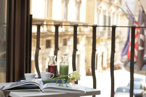 una mesa con un libro abierto y dos vasos y un libro en Santacroce Luxury Rooms, en Lecce