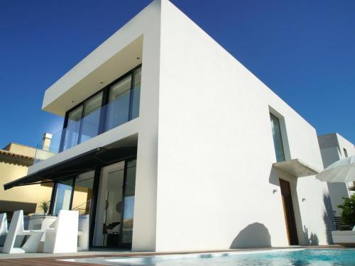ein weißes Haus mit einem Pool davor in der Unterkunft Atzur in Son Serra de Marina