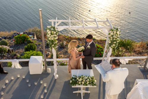 a bride and groom at their wedding ceremony on the deck at Asma Suites in Fira
