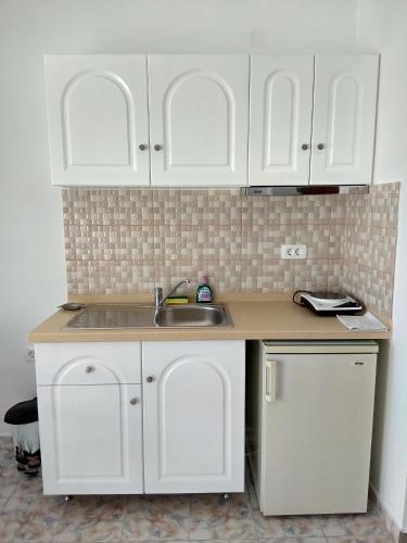 a kitchen with white cabinets and a sink at Margarita in Perissa